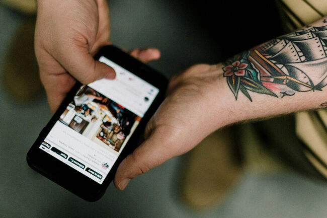 Tattooed man with smartphone in hand