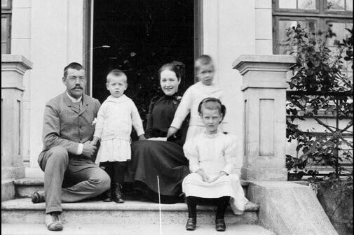 Familien Bohr foran Nærumgaard, familien Adlers sommerresidens, i 1890. Her ses Christian Bohr, Ellen Bohr født Adler og deres tre børn Jenny Bohr, Niels Bohr og Harald Bohr. Niels Bohr står bag sin søster til højre.