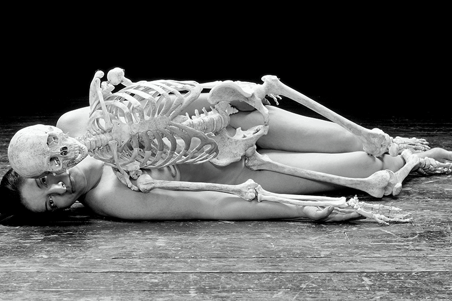 Marina Abramović is lying naked on the floor with a skeleton on top of her