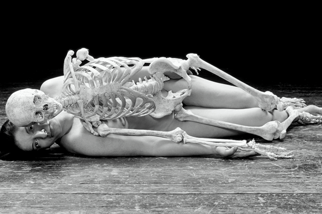 Marina Abramović is lying naked on the floor with a skeleton on top of her